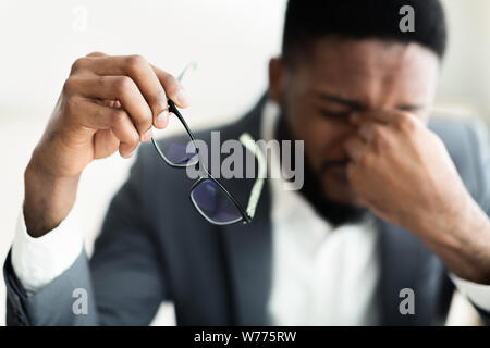 Fatigué african businessman en tenant ses lunettes Banque D'Images
