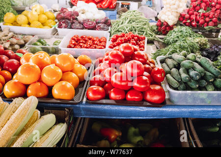 Comptoir à un marché de la rue des agriculteurs avec des tomates, oignons verts, maïs, choux, concombres, radis, citrons et herbes fraîches. Les tomates biologiques sur la co Banque D'Images