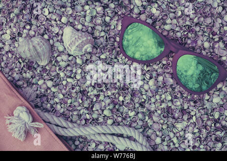 Scène de plage. Sac de plage et lunettes de soleil couché sur coquilles coquina mer Banque D'Images