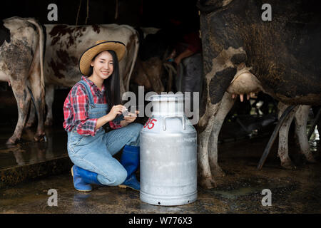 Les femmes asiatiques l'agriculture et l'industrie de l'agriculture et l'élevage concept - les jeunes femmes ou de l'agriculteur avec ordinateur tablet pc et les vaches laitières en étable sur Banque D'Images