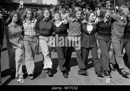 Les bras des adolescentes se sont réunis en s'amusant, regardant les années 1970 élégantes au gala annuel des mineurs de charbon de Durham County Durham UK 70s. Un garçon au milieu. Toutes les filles portent des pantalons.1974 Angleterre HOMER SYKES Banque D'Images