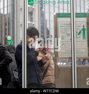 Tokyo, Japon - 15 mai 2019 : Les fumeurs debout dans un espace fumeurs dans la ville. Banque D'Images