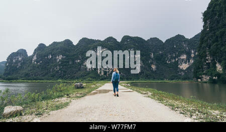 Young blonde woman walking vers llimestone montagnes à Ninh Binh, Vietnam. Banque D'Images