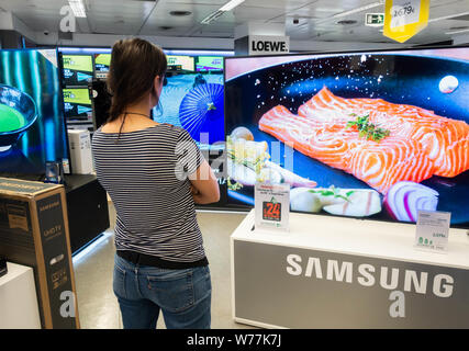 Femme à la recherche de nouveaux Samsung 4k haute définition télé des courbes store électrique Banque D'Images