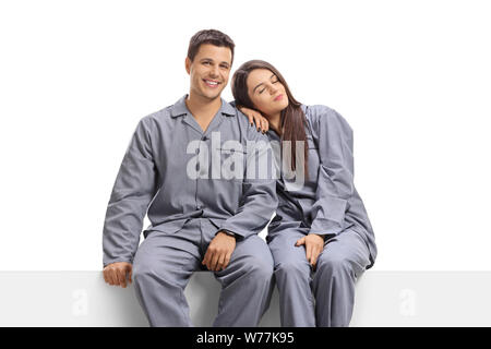 Jeune homme et femme en pyjama assis sur un panneau isolé sur fond blanc Banque D'Images