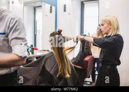 Portrait de femme heureuse au salon de coiffure. Coiffure professionnel concept. Coiffure cheveux longs fille de séchage en utilisant un sèche-cheveux et d'un pinceau. Avec le séchage Banque D'Images