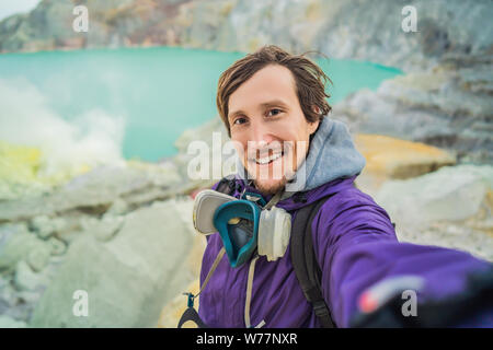 Jeune homme fait un touriste permanent selfies au bord du cratère du volcan Ijen Kawah Ijen ou sur la langue indonésienne. Célèbre volcan Banque D'Images