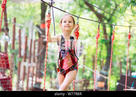 Happy school girl enjoying activité dans un parc aventure escalade un jour d'été, Banque D'Images