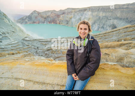 Jeune femme assise touristique au bord du cratère du volcan Ijen Kawah Ijen ou sur la langue indonésienne. Célèbre volcan contenant le Banque D'Images