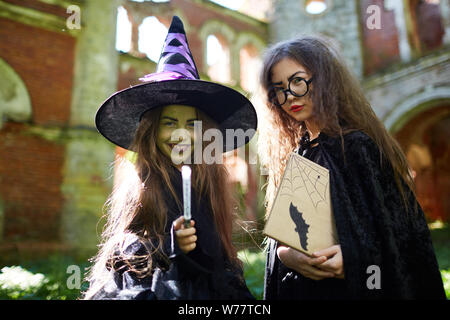 Taille portrait de deux petites sorcières looking at camera tout en se posant dans le château abandonné sur Halloween Banque D'Images