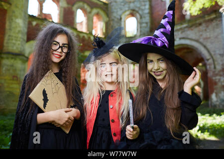 Taille portrait de trois petites sorcières looking at camera tout en se posant dans le château de Spooky Halloween sur Banque D'Images