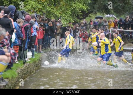 Une tradition britannique, le football fluvial à Bourton-on-the-Water, Cotswolds, août 2015. Le match se tient tous les jours fériés d'août. Le match est un match de football à cinq, mais dans la rivière Windrush qui traverse la ville. Les résidents et les visiteurs bordent le bord de l'eau et les ponts pour obtenir les meilleurs sièges, mais risquent de se tremper si l'action se rapproche trop. En 2015, Griff Rhys Jones, célèbre britannique, a participé au tournage d'UNE grande aventure britannique. Crédit: Michael Scott/Alay Live News Banque D'Images