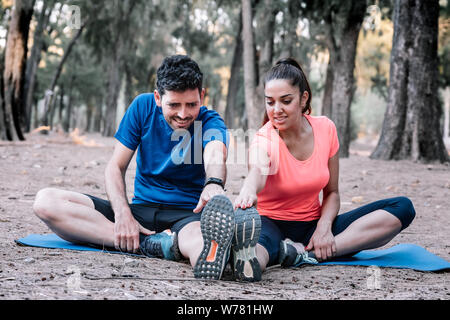 Couple assis dans un parc, faire des exercices d'étirement Banque D'Images