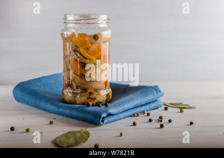 Champignons marinés dans un bocal en verre sur un fond blanc Banque D'Images