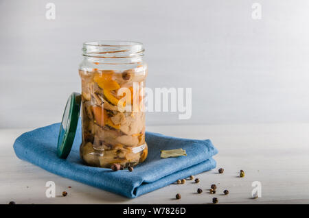 Champignons marinés dans un bocal en verre sur un fond blanc Banque D'Images