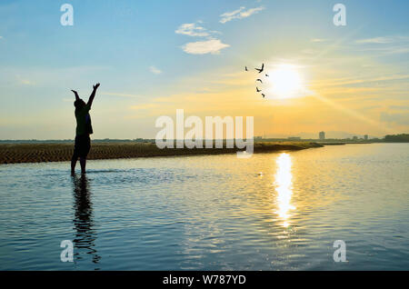 Silhouette de l'homme levant les mains ou bras ouverts lorsque le coucher du soleil Banque D'Images