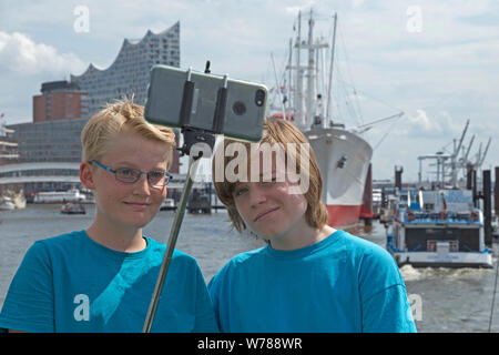 Les adolescents pendant l'étude d'une langue prise voyage autoportraits en face de la Philharmonie de l'Elbe, Hambourg, Allemagne Banque D'Images
