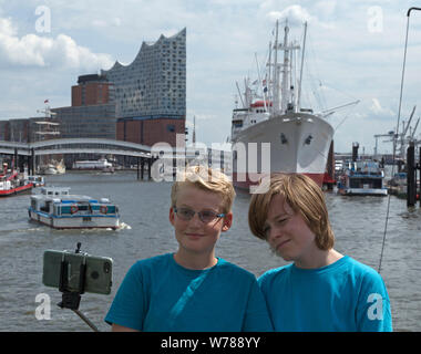 Les adolescents pendant l'étude d'une langue prise voyage autoportraits en face de la Philharmonie de l'Elbe, Hambourg, Allemagne Banque D'Images