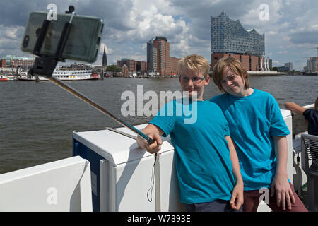 Les adolescents pendant l'étude d'une langue prise voyage autoportraits passant Elbe Philharmonic Hall sur un ferry, Hambourg, Allemagne Banque D'Images