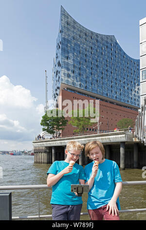 Les adolescents pendant l'étude d'une langue prise voyage autoportraits en face de la Philharmonie de l'Elbe, Hambourg, Allemagne Banque D'Images