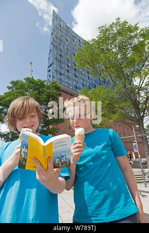 Les adolescents pendant l'étude de leur voyage d'étude de la langue Dictionnaire allemand en face de la Philharmonie de l'Elbe, Hambourg, Allemagne Banque D'Images