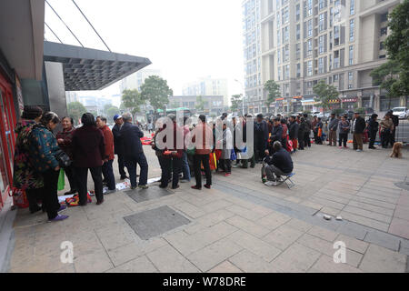 Les résidents de récupérer leurs propres sacs et attendre en ligne pour acheter moins cher le riz en face d'un supermarché de la ville de Anqing, Chine de l'est l'Anhui province, 15 Banque D'Images