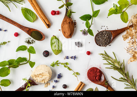 De l'air : la maca en poudre, poudre de betterave, Chia et le chanvre, la spiruline dans des cuillères en bois sur un fond blanc. Concept de saine alimentation. Banque D'Images