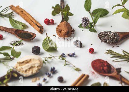 De l'air : la maca en poudre, poudre de betterave, Chia et le chanvre, la spiruline dans des cuillères en bois sur un fond blanc. Concept de saine alimentation. Banque D'Images