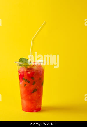 De smoothie pastèque rouge mûr dans une tasse en plastique, Close up, fond jaune Banque D'Images