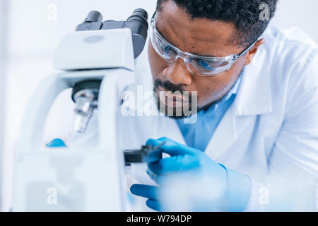 L'homme ne la recherche scientifique avec le microscope dans le laboratoire. Banque D'Images