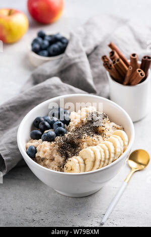 Bouillie d'avoine dans un bol de fruits, graines de chia, la cannelle sur table béton. Focus sélectif. Nettoyer alimentaires, les régimes, perte de poids, forme physique concep menu Banque D'Images