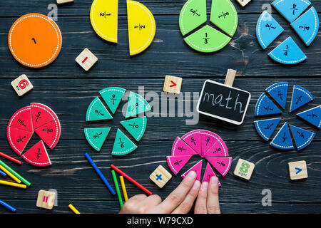 Les enfants se déplace à la main sur des fractions mathématiques colorés en bois sombre arrière-plan ou table. Intéressante de création de funny math pour les enfants. L'éducation, de nouveau à l'école concep Banque D'Images