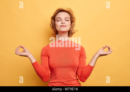 Close up portrait of merveilleuse jeune femme détendue en gardant les yeux fermés tout en méditant, pratiquant le yoga, gardant les doigts dans mudra geste. frv en bonne santé Banque D'Images