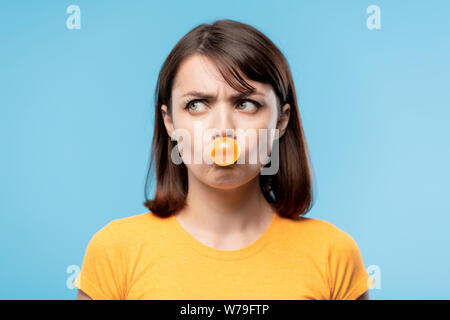 Une adolescente brune soufflant de la bulle de chewing-gum jaune Banque D'Images