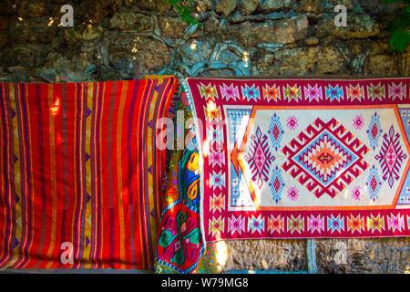 Brodé de fils de tapis de différentes couleurs. Les tapis sont accrochées sur un mur de pierre dans un marché turc. Banque D'Images