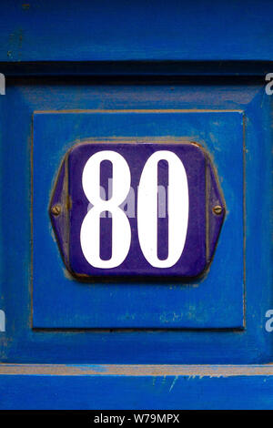 Signe avec l'émail bleu numéro de maison 80 en gras sur porte avant en bois bleu foncé Banque D'Images