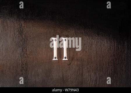 Numéro de la maison à 11 chiffres en métal argenté sur une porte en bois noir Banque D'Images