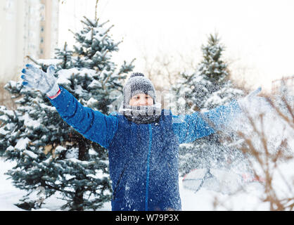 Happy cute excited boy adolescent joue avec la neige, fait boule de neige. Activité d'hiver, des loisirs actifs et de divertissement concept. Banque D'Images