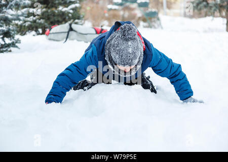 Happy cute excited boy adolescent joue avec la neige, fait boule de neige. Activité d'hiver, des loisirs actifs et de divertissement concept. Banque D'Images