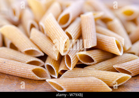 Close up de penne des pâtes alimentaires de blé entier sur table en bois.