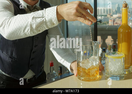 Barman est en remuant cocktail avec des cubes de glace en verre à mélange Banque D'Images