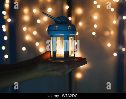 Kid est titulaire Noël lanterne dans les mains sur l'arrière-plan flou d'éclairage de nuit. Nouvel an fête concept, ambiance de fête, Banque D'Images