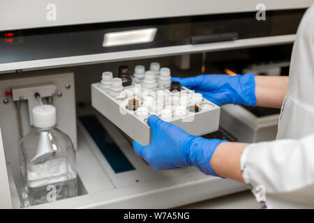 Technicien de laboratoire l'examen du sang dans l'analyseur automatique de l'échantillon de sang. Banque D'Images