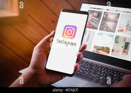 Bangkok, Thaïlande - 6 août 2019 : Hands holding Smartphone avec Instragram Instragram sur l'écran du logo et site web sur fond d'ordinateur portable. Instagram est la Banque D'Images