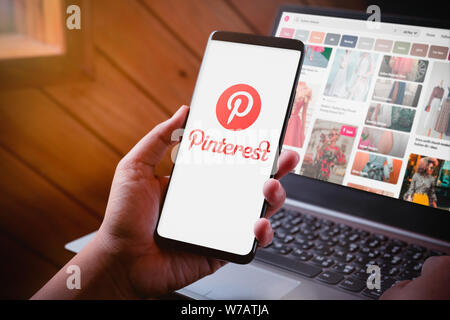 Bangkok, Thaïlande - 6 août 2019 : Hands holding Smartphone avec l'écran du logo et Pinterest Pinterest site sur fond d'ordinateur portable. Pinterest est un Banque D'Images