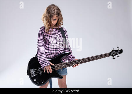 Jeune joueur de guitare avec une guitare électrique debout avec la tête inclinée sur fond gris clair avec copie espace Banque D'Images