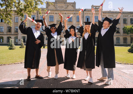 Heureux les élèves debout devant l'université. Banque D'Images