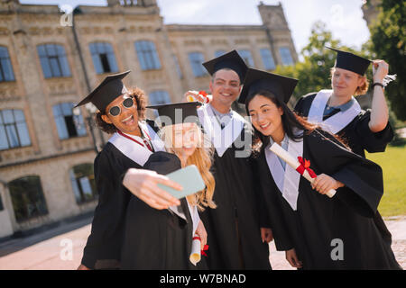 Cheerful groupmates en tenant vos autoportraits après leur graduation. Banque D'Images