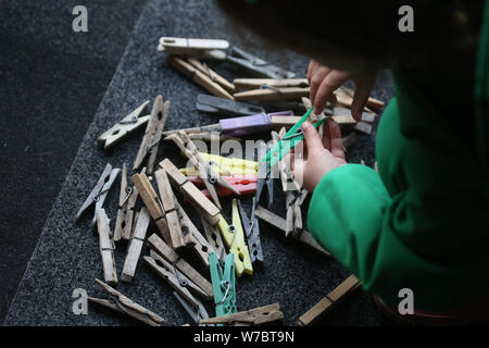 Les détails avec les mains d'une petite fille jouant avec des pinces en plastique et en bois sur un fil Banque D'Images