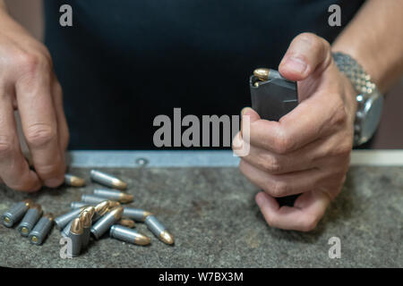 Un homme dans un T-shirt noir porte-charges le pistolet avec 919 cartouches. Les mains des hommes pour charger le pistolet avec munitions. close-up. Banque D'Images